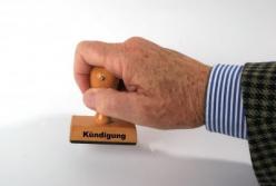 Das Bild zeigt einen Mann, der einen Stempel mit dem Aufdruck "Kündigung" verwendet