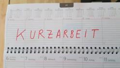 Das Bild zeigt einen Tischkalender mit einer Eintragung "Kurzarbeit" in roter Farbe 