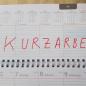 Das Bild zeigt einen Tischkalender mit einer Eintragung "Kurzarbeit" in roter Farbe 